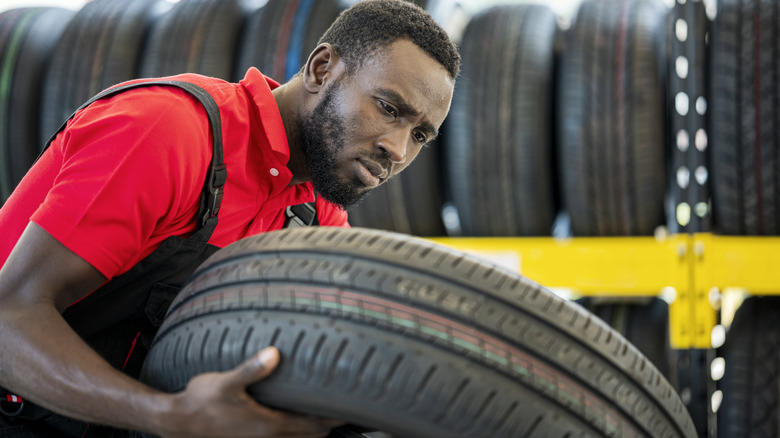specialist examines tire at shop