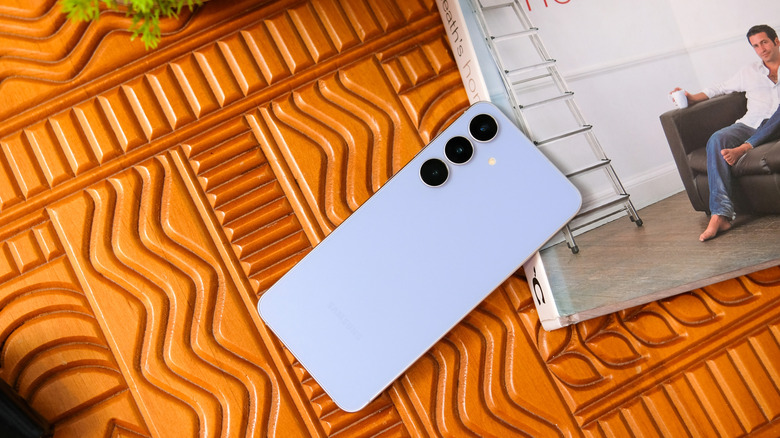 A blue Samsung phone next to a book.