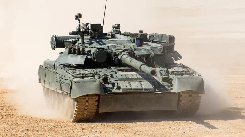 A tank driving across sand.