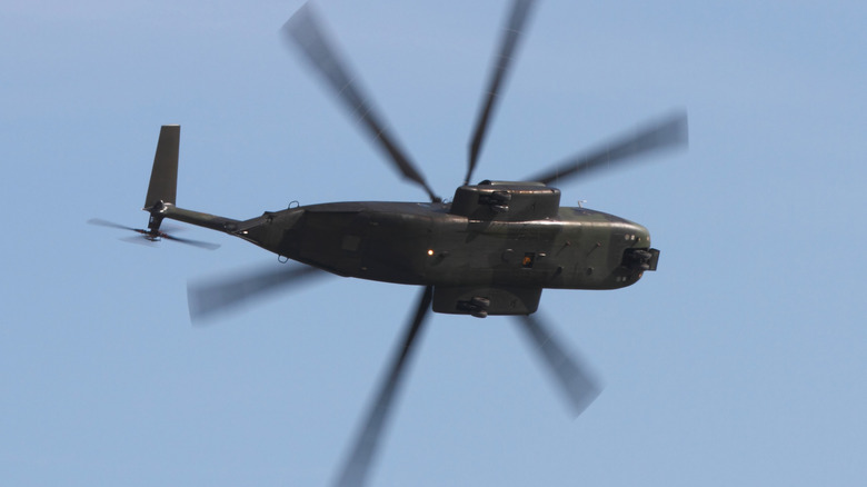 A military helicopter flying as seen from the ground.