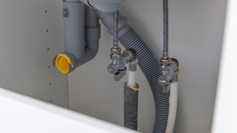 Close-up of water tubes under a sink.