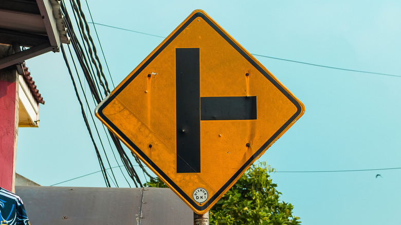 Close-up of a T-Intersection warning sign showing the upcoming joining road is on the right