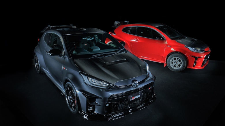 Two Toyota Yaris GRMN models side-by-side in photo booth, front and right-side views