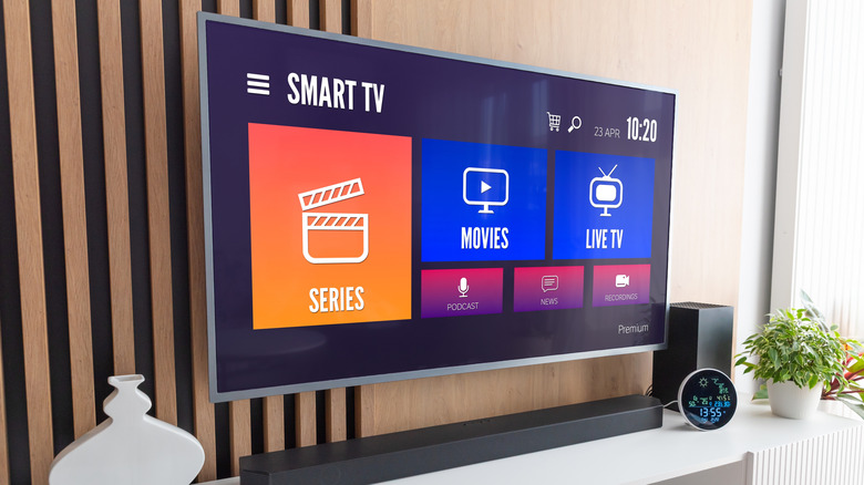Smart television mounted on a wall above a media center and soundbar.