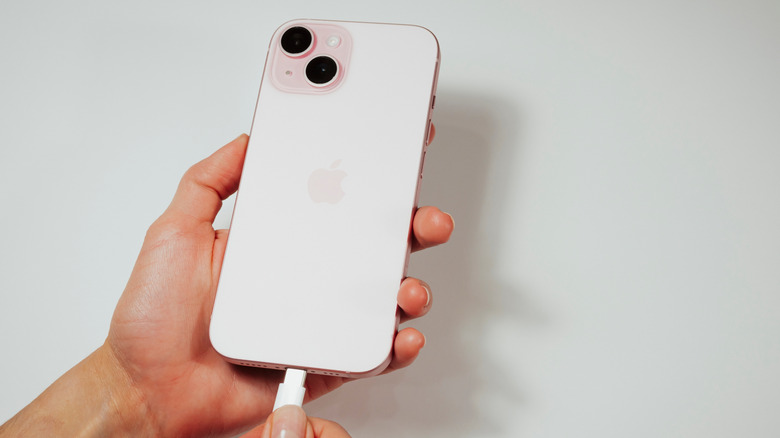Person holding white iPhone and plugging in charger