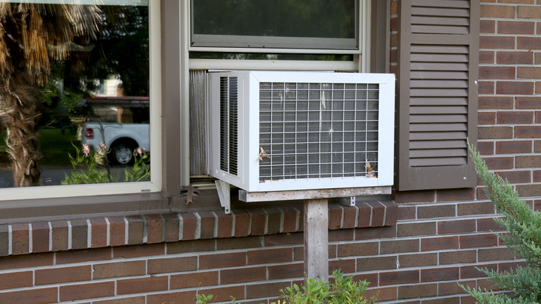 A window conditioner unit mounted on the window of a brick house