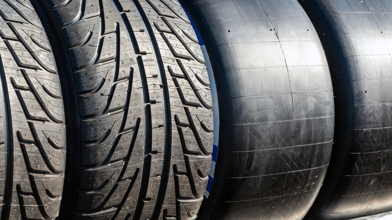 A close-up of racing and street tires side by side showing rubber and tread