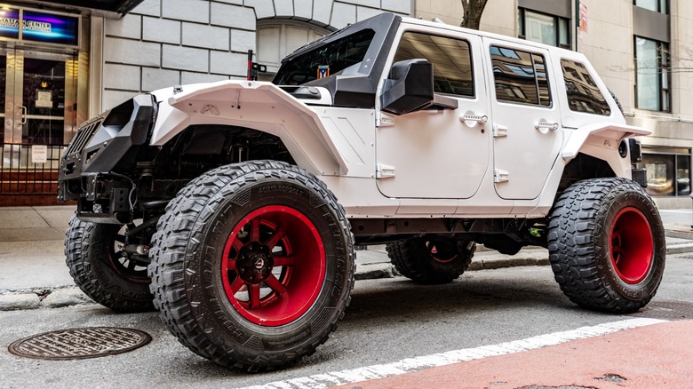 A four-door Jeep Wrangler with big off-road tires mounted on negative-offset wheels