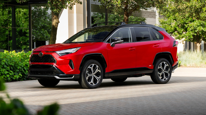 Red 2025 Toyota RAV4 PHEV XSE parked on a paved surface in front of a building