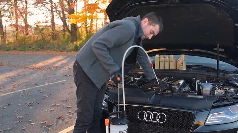 a person using an oil extractor to replace their engine oil
