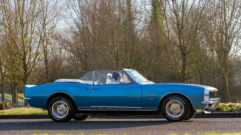 A blue 1967 Chevrolet Camaro convertible on the move, side view