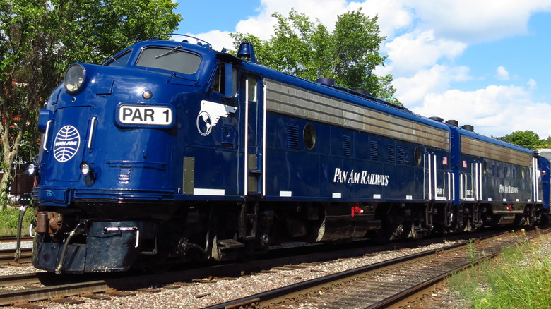 Blue EMD FP9A locomotive bearing Pan Am branding on tracks with trees in the background.