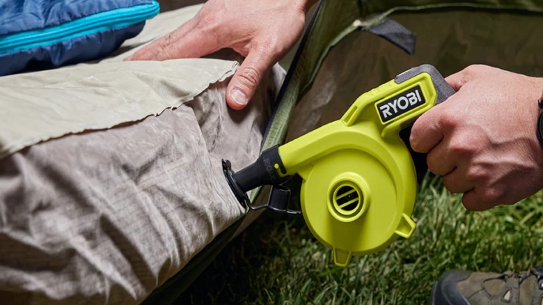 A person using a Ryobi 4V inflator on an air mattress.
