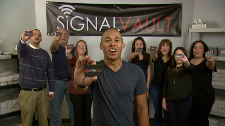 Chris and SignalVault team holding cards under banner