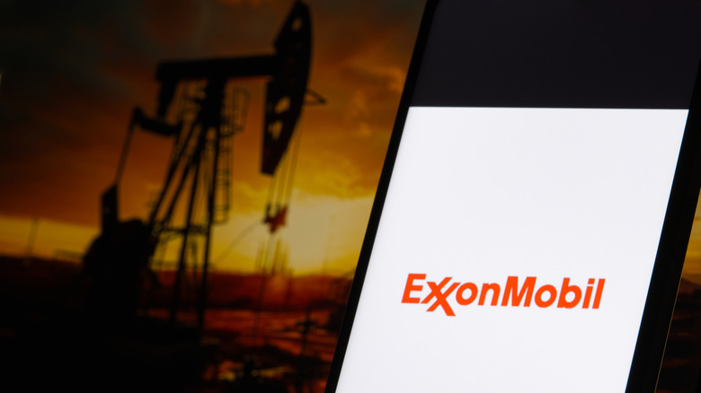 An ExxonMobil symbol on a phone is shown before an oil drill