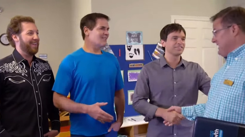 Chris, Mark, and Dave shaking hands with school representative