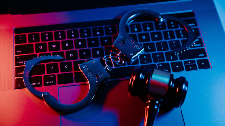 A gavel and handcuffs on top of a laptop keyboard