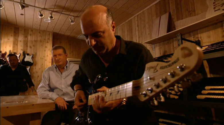 Kevin O'Leary playing guitar while Jeff sits in the background
