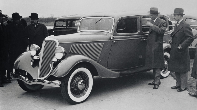 A 1934 Model Ford V8 shown by Henry Ford and his son Edsel with new radiator design and whitewall tires.