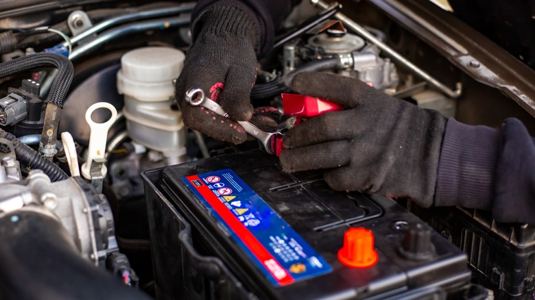 A mechanic replacing old car battery under the hood