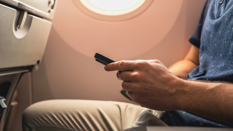 Man using phone on airplane
