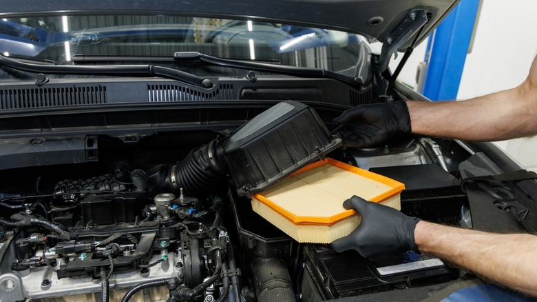 Mechanic hands replacing car engine air filter