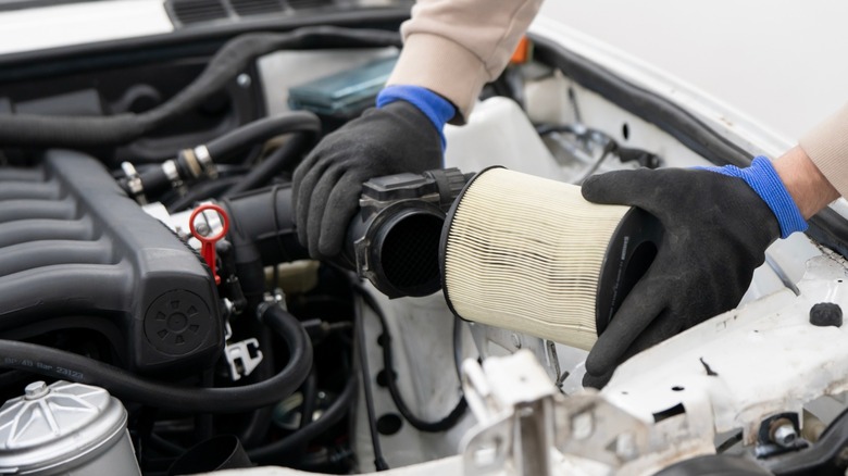 Mechanic hands replacing car engine air filter