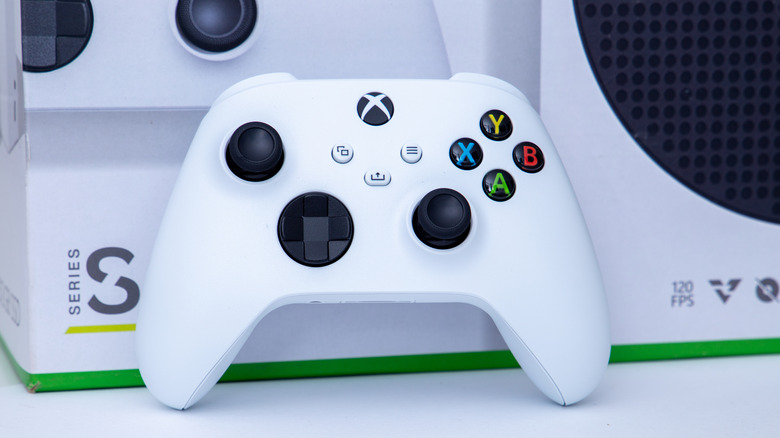 A white Xbox controller leaning against the box of an Xbos Series S console