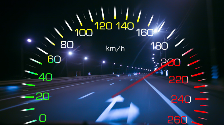 Close-up view of a car speedometer crossing 200kph with a road on the background