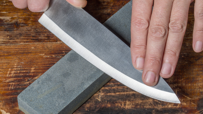 A person sharpening a knife on a whetstone.