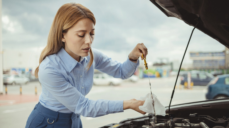 Woman checking level of oil using a dipstick