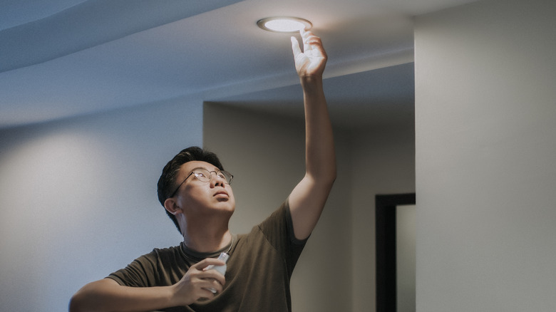 man switching out lightbulb at home