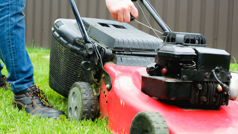 A man trying to start a walk-behind mower