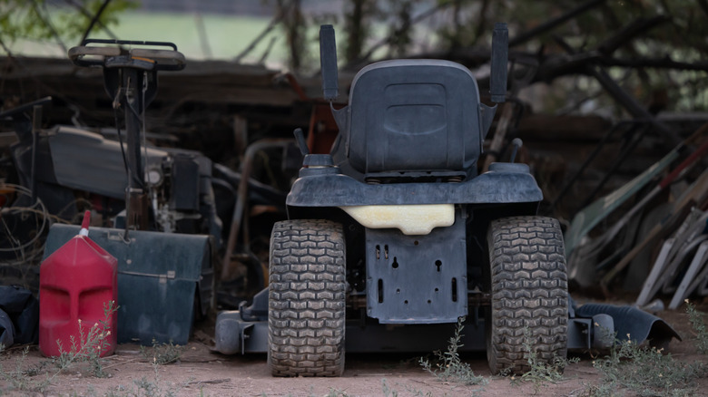 An old riding mower and gasoline container stored outside