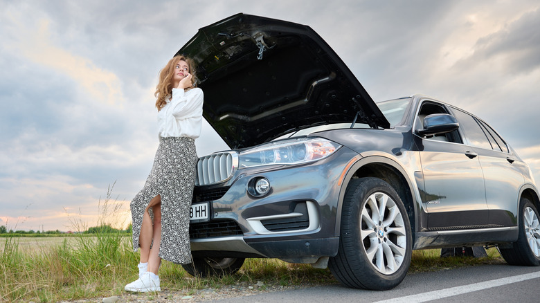 Woman with car broken down on side of road in rural area