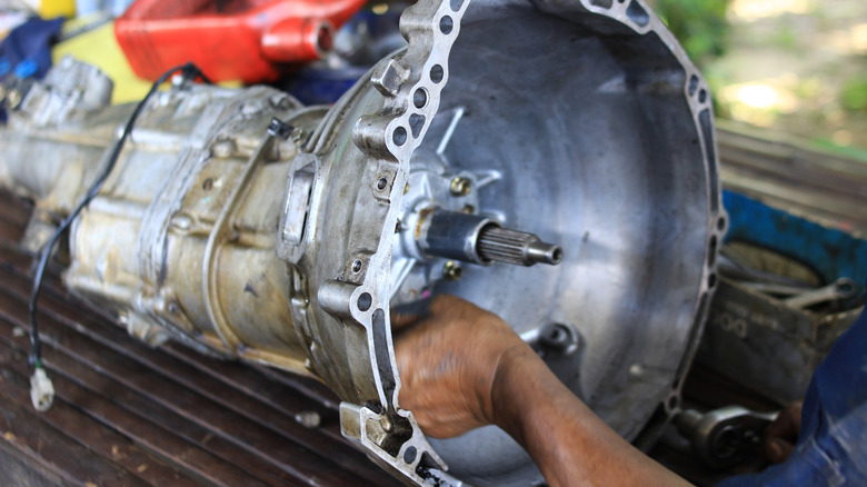 Close shot of transmission with mechanic's hand making repairs