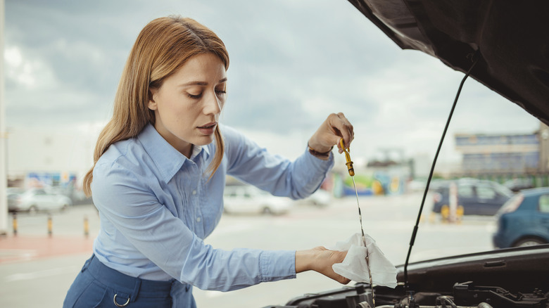 Woman driver inspecting the oil level with the dipstick