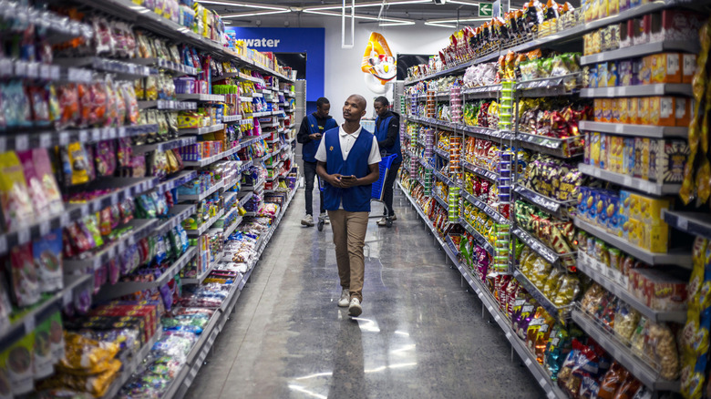 Walmart employees walking through aisle.