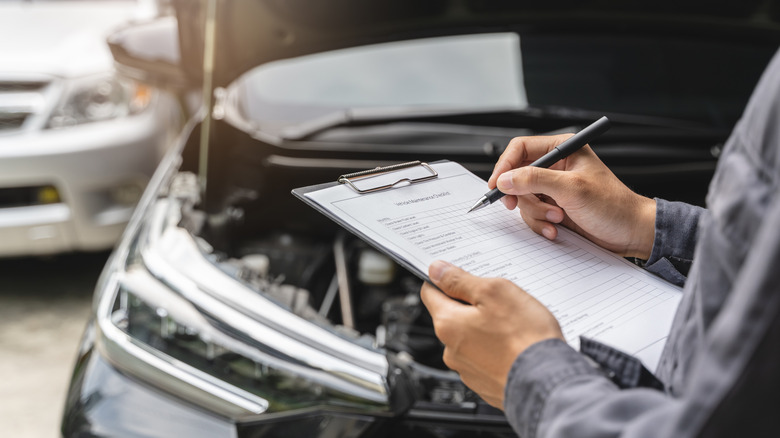 An insurance provider checking a damaged car
