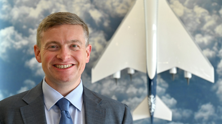 Boom Founder and CEO, Blake Scholl poses by a model of the Overture Supersonic Airliner during the Farnborough International Airshow