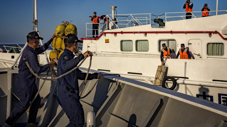 Philippine Coast Guard personnel of BRP Sindangan and Chinese Coast Guard personnel deploy fenders as they brace for a collision