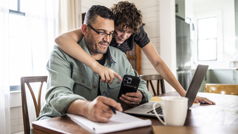 Kid showing older man how to use iPhone