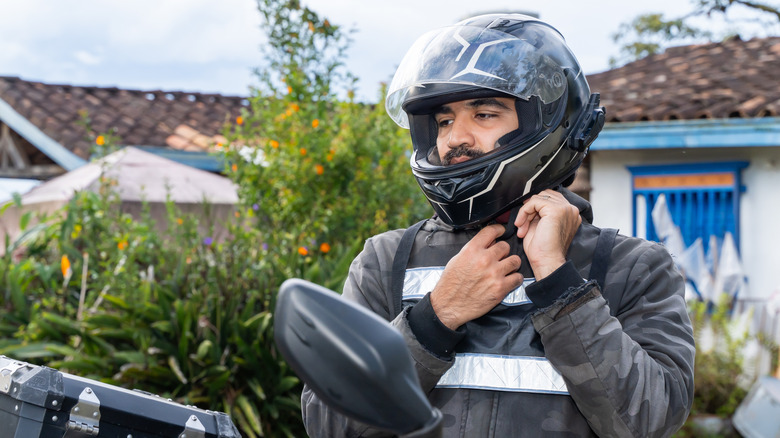Person adjusting the strap of their motorcycle helmet.