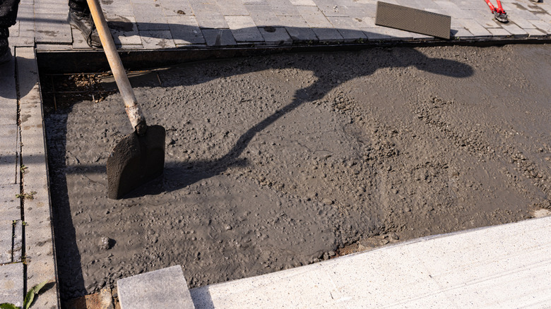 Shovel sticks face-down in rectangular patch of wet concrete