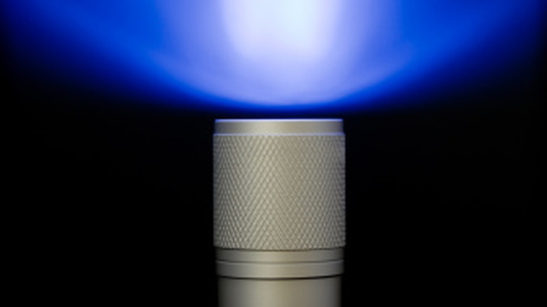 A blue light flashlight against black surface