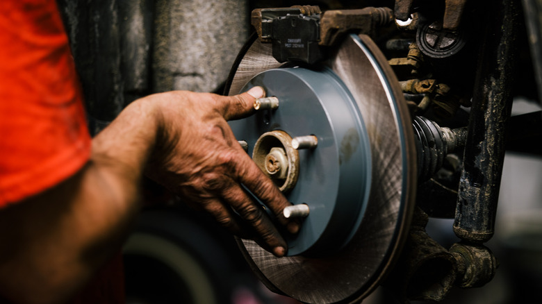 A mechanic in a red T-shirt working on a car braking system