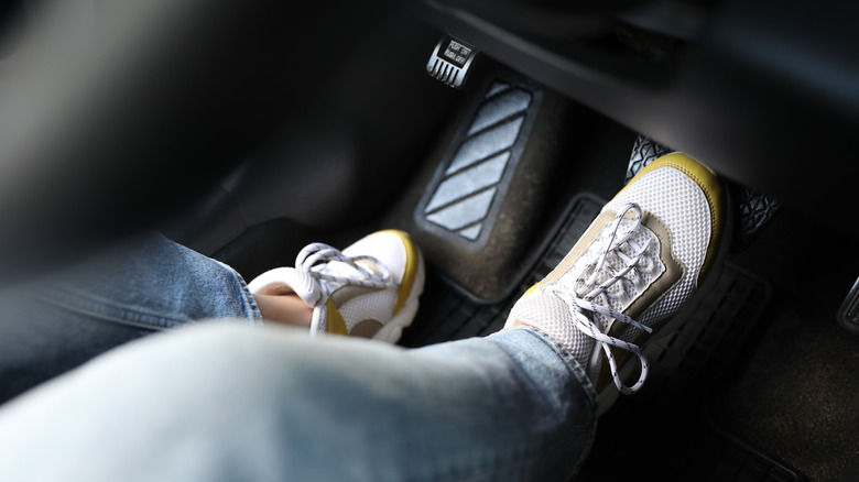 A person in sneakers pressing on the brake pedal