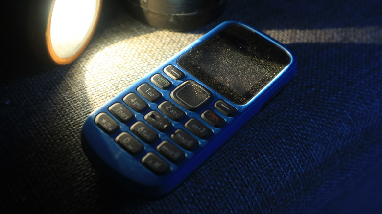 Older blue cell phone handset in the light of a flashlight