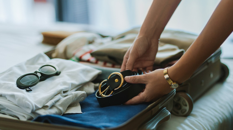 Someone packing a suitcase with clothes