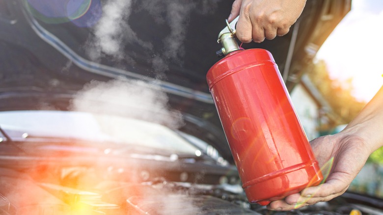 Person uses fire extinguisher in open car hood